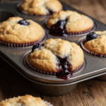 close up of easy homemade blueberry muffins in a rustic muffin tin golden tops with bursting bluebe x6kf40gc5b8syzjvh911 1