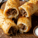 Golden cheesy taco sticks filled with seasoned beef and gooey melted cheese, served with bowls of salsa, taco rice, and sour cream on the side.