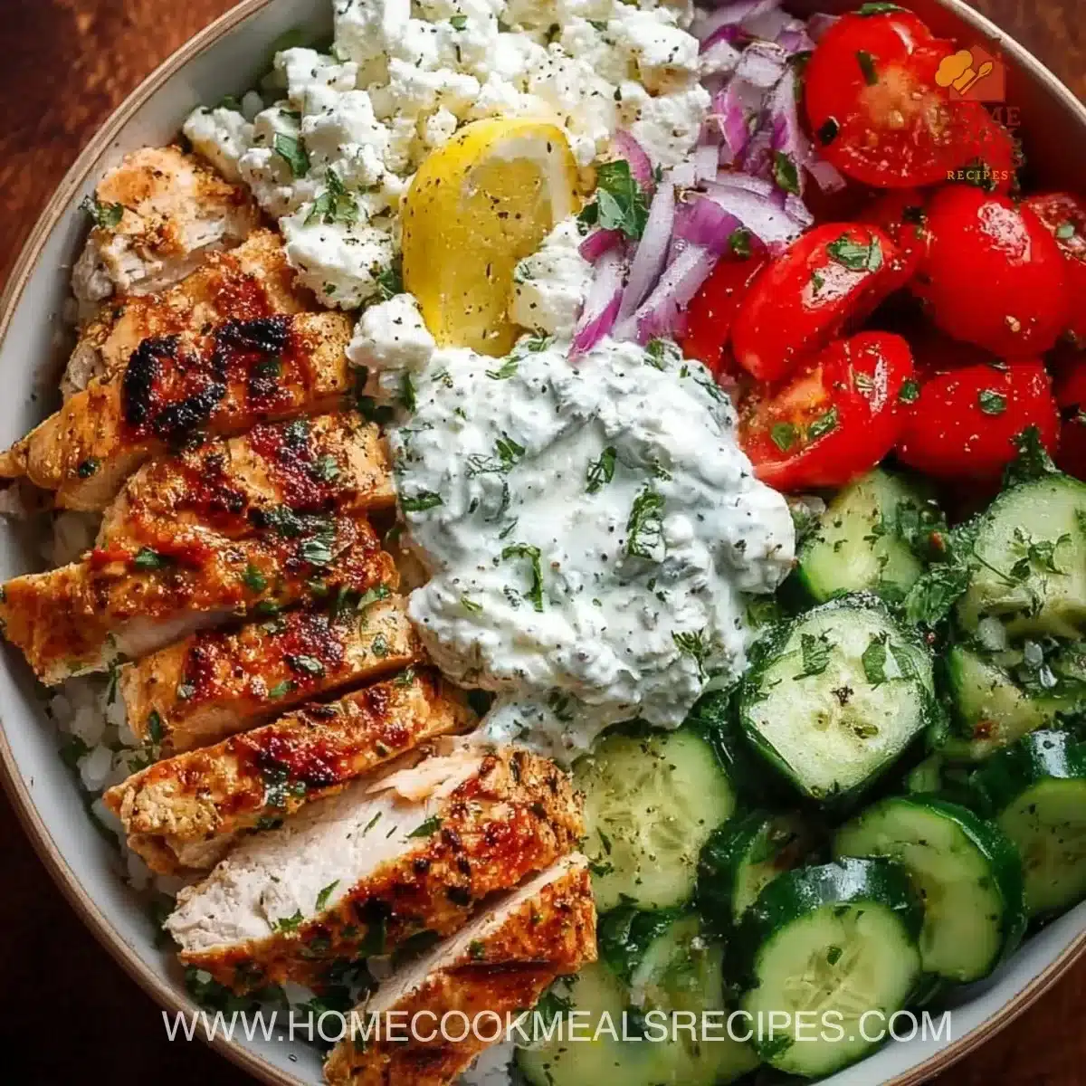 Delicious Greek Chicken Bowls garnished with fresh vegetables and tzatziki sauce