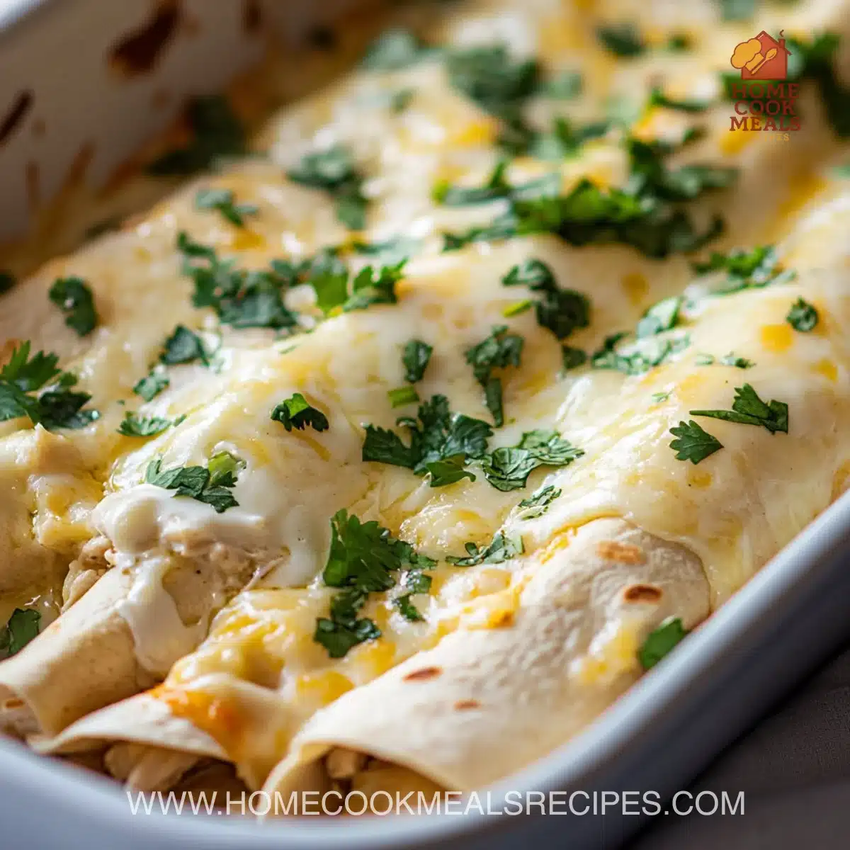 Creamy white chicken enchiladas topped with sauce and cheese on a plate